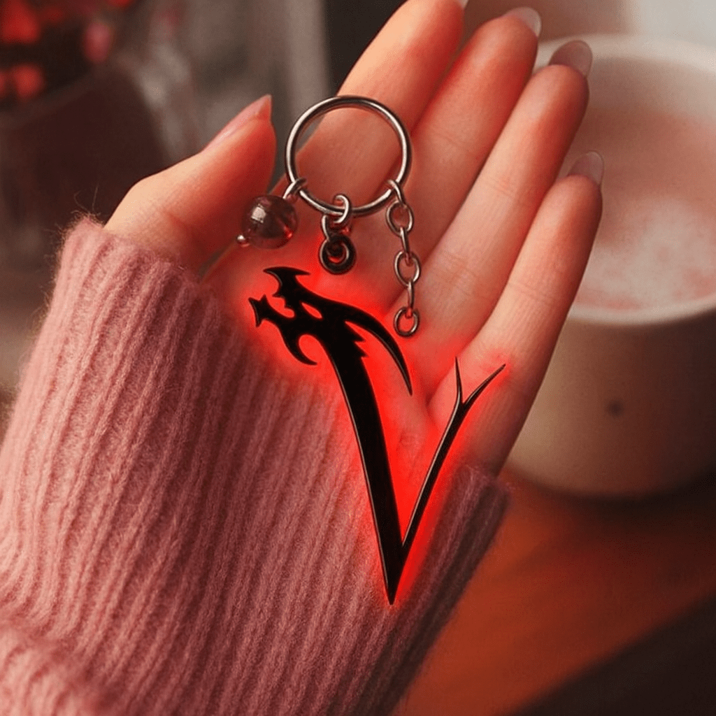 A person holds a keychain featuring a prominent red and black letter V design