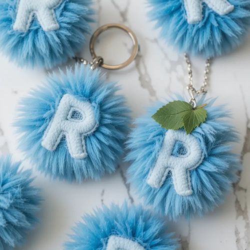 R DP Name ProProfileDP_ The letter 'R' appears twice on fluffy, round, blue fur keychains, giving a playful and cozy vibe. A small green leaf accentuates the design