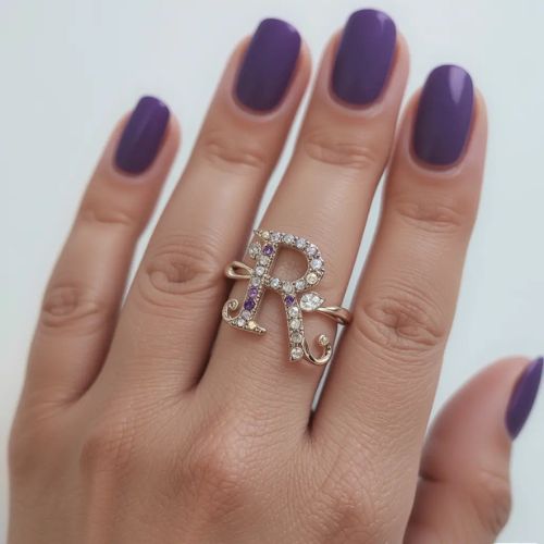 R DP Name ProProfileDP_ _The letter R takes center stage on a crystal-studded ring, perfectly paired with matte purple nails for a sophisticated finish