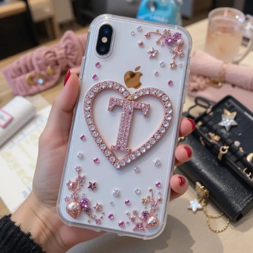 The letter _T_ placed within a heart shape on a clear phone case, surrounded by rhinestones