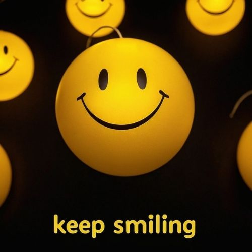 A glowing yellow smiley face ball with 'Keep Smiling' text, surrounded by heart decorations on a dark background, radiating warmth and positivity.