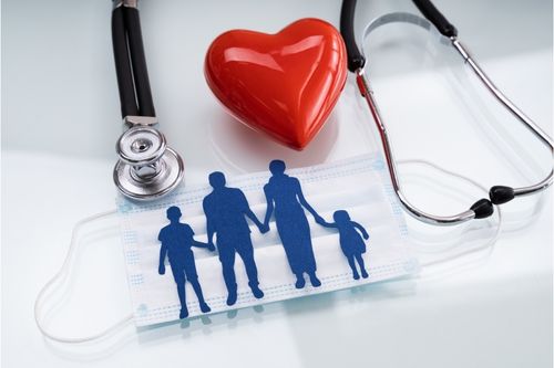 A stethoscope, a red heart model, and a face mask featuring a blue silhouette of a family holding hands, symbolizing healthcare, family protection, and medical well-being.