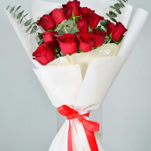 A bouquet of vibrant red roses elegantly wrapped in crisp white paper