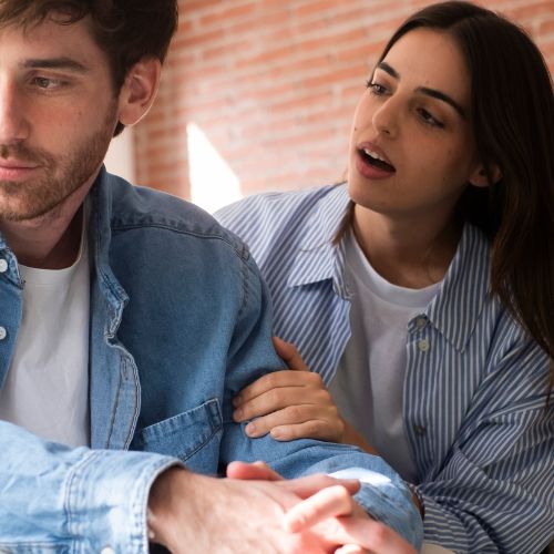 A man and woman are focused on a laptop screen, engaged in discussion or collaboration