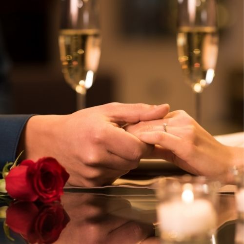 A man and woman holding hands while toasting with champagne glasses