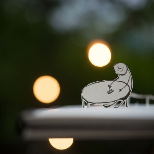 A paper cutout depicting a person seated at a table, showcasing a simple and artistic representation