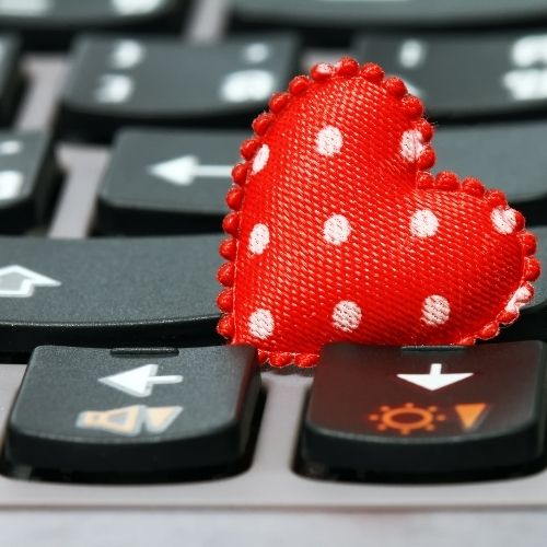 A red heart rests on a keyboard featuring a playful polka dot pattern
