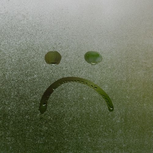 A sad face etched in frost on a window, conveying a sense of melancholy and coldness