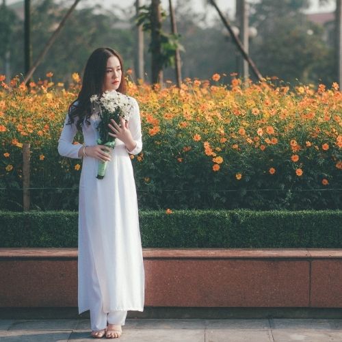 A woman in a white dress holds a vibrant bouquet of flowers
