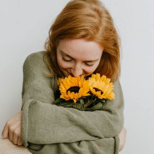 A woman joyfully hugs a large sunflower showcasing her love for nature