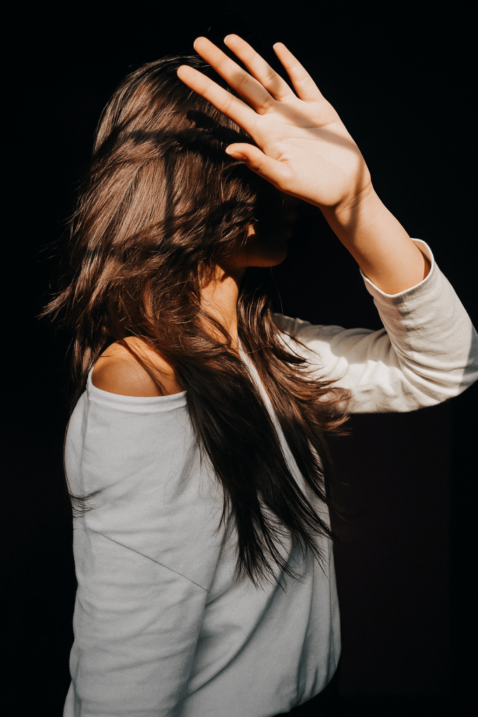 A woman joyfully raises her hands in the air, expressing excitement or celebration