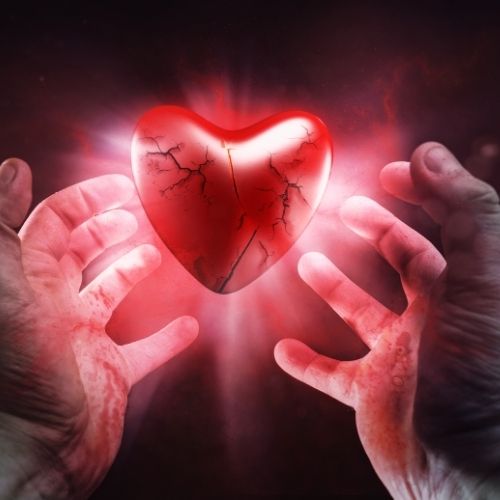 Hands gently holding a broken heart, symbolizing emotional pain and heartbreak.