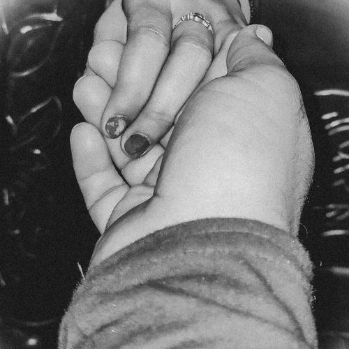 A black and white photo of a couple gently holding hands, symbolizing love and connection
