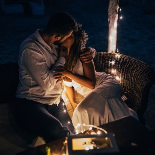 A couple sharing a romantic kiss in the dark of night, silhouetted against a starry sky