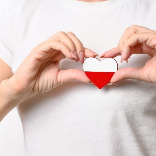 A woman forms a heart shape with the Polish flag, symbolizing love and pride for her country
