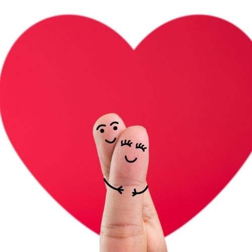 Happy couple holding hands with a large heart in the background, symbolizing love and connection