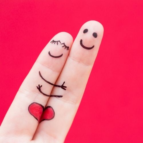 Happy couple's fingers with smiley faces on a vibrant red background