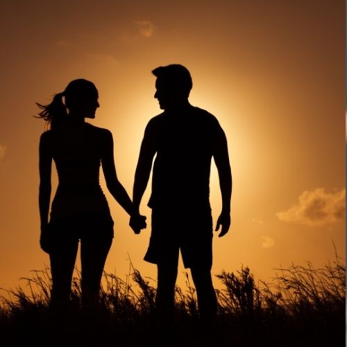 Silhouette of a couple holding hands against a vibrant sunset backdrop, symbolizing love and connection