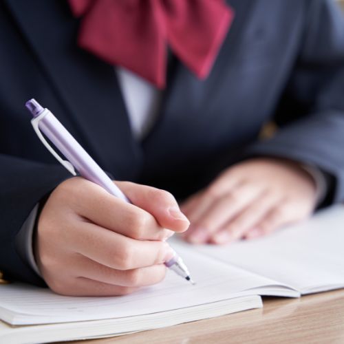 A person in a suit is writing on a piece of paper