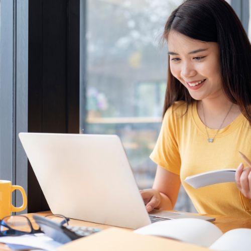 A woman smiles while working on her laptop