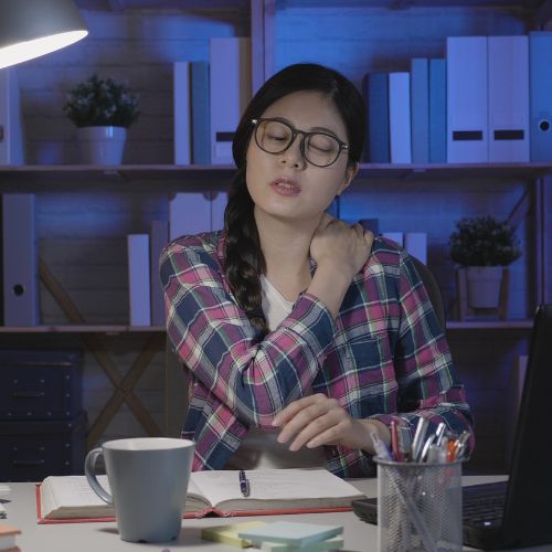 A woman with glasses is seated at a desk