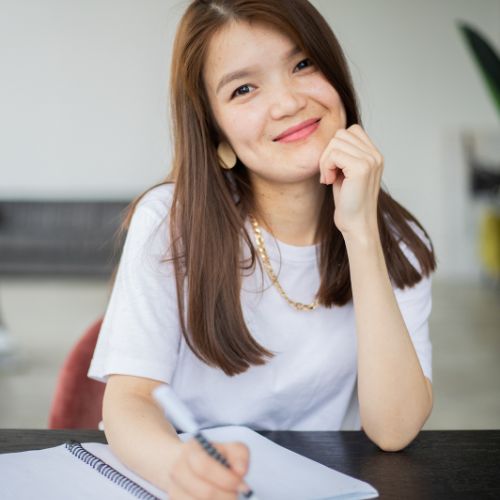A young woman smiles while seated at a table