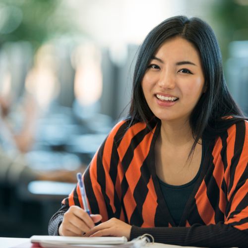 A young woman with a bright smile sits at a table, radiating joy and friendliness
