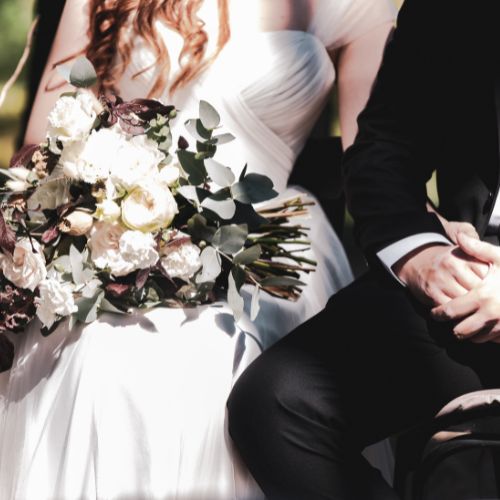 A bride and groom sit on a bench