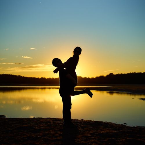 Silhouette of a couple embracing each other against a vibrant sunset backdrop