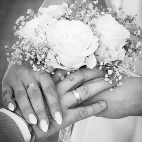 A black and white photo of a bride and groom holding hands