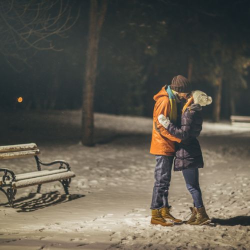 A couple sharing a romantic kiss in a snowy landscape