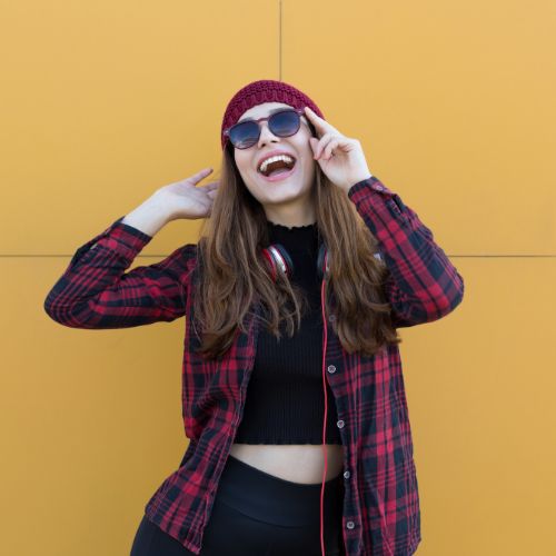 A girl wearing a plaid shirt and sunglasses is joyfully laughing and smiling