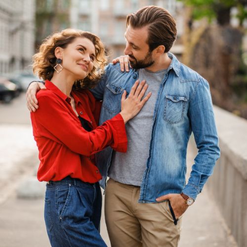 A man and woman embrace warmly in a bustling stree