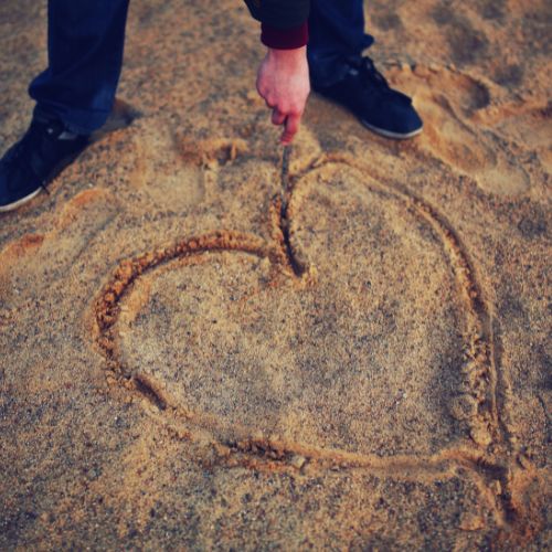 A person kneels on the beach