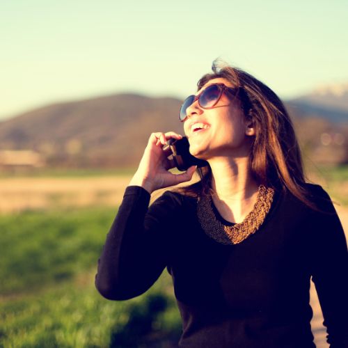 A woman wearing sunglasses is talking on a cell phone