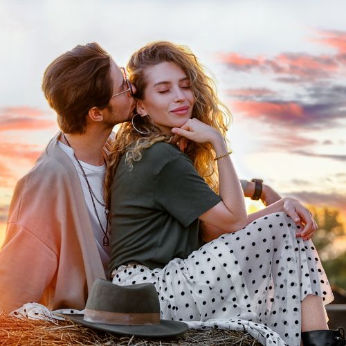 A young couple sits on a hay bale
