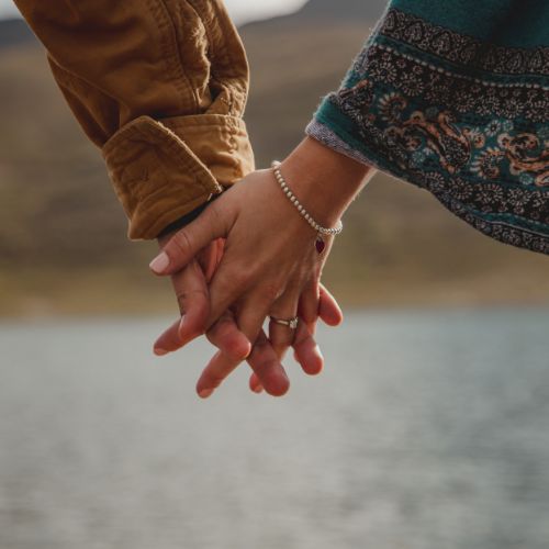 Couple holding hands while standing by a serene lake