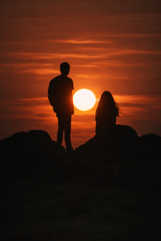 Silhouette of a couple standing on a rock at sunset